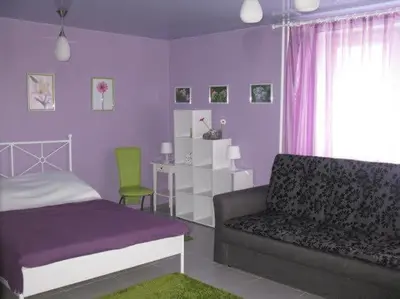 a purple bedroom with a bed and a couch at Apartamentai Atostogos in Druskininkai
