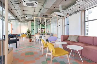 a living room with a couch and tables and chairs at SHED Coliving studio in Vilnius