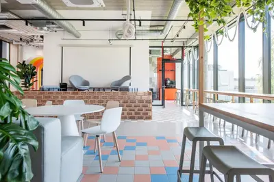 an office space with tables and chairs and plants at SHED Coliving studio in Vilnius