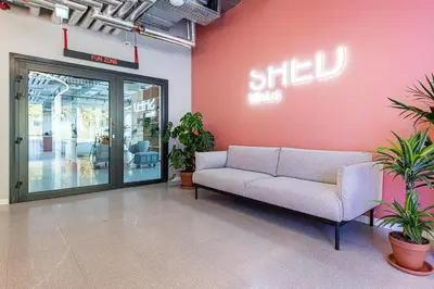 a couch in a lobby with a sign on a wall at SHED Coliving studio in Vilnius