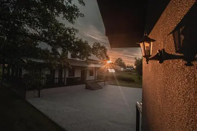 a sunset behind a building with a street light at Vėjo Malūnų sodyba - Didžioji vila in Paserninkai