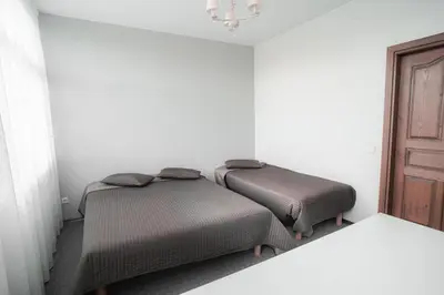 two beds in a room with white walls and a door at Vėjo Malūnų sodyba - Didžioji vila in Paserninkai