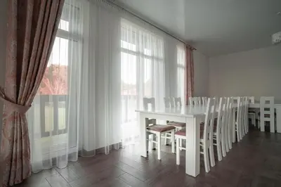 a white table and chairs in a room with windows at Vėjo Malūnų sodyba - Didžioji vila in Paserninkai