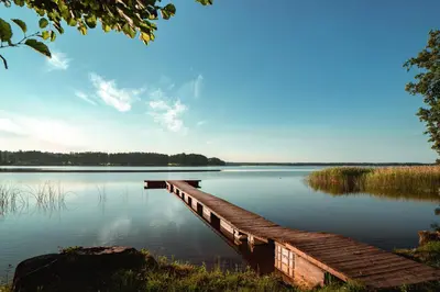 a dock on a lake with a blue sky at Vėjo Malūnų sodyba - Didžioji vila in Paserninkai