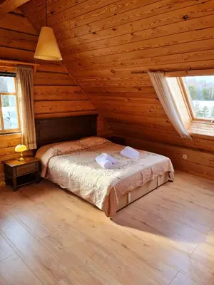 a bedroom with a bed in a wooden cabin at Asvejos sodyba in Skirlėnai