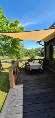 a wooden deck with a table on a house at Asvejos sodyba in Skirlėnai