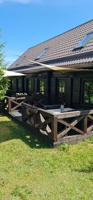 a house with a wooden deck in the grass at Asvejos sodyba in Skirlėnai