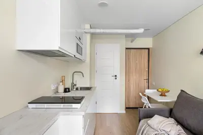a white kitchen with a sink and a couch at GOOD LOCATION studio near the old town - station - airport - self check in in Vilnius
