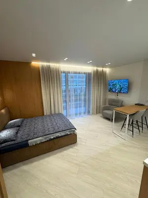 a bedroom with a bed and a living room at V4 Europa New Apartment in Vilnius