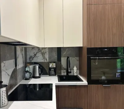 a kitchen with white cabinets and black appliances at Studio in Oldtown in Vilnius