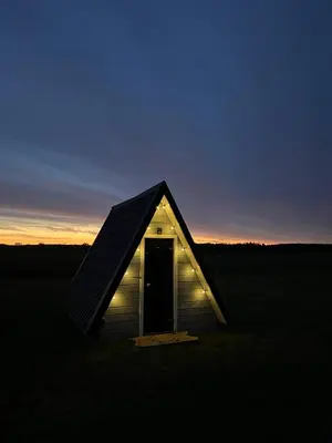 a small house in a field at sunset at A-Spot - A-formos nameliai ir poilsio sodyba in Roglaičiai I