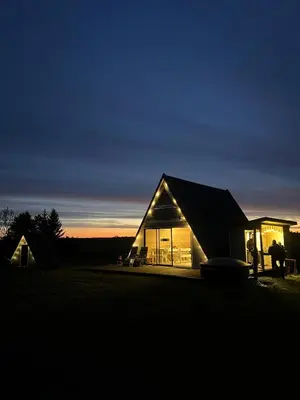 a house is lit up at night in a field at A-Spot - A-formos nameliai ir poilsio sodyba in Roglaičiai I