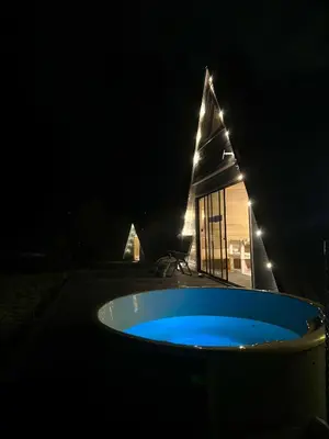 a hot tub in front of a house at night at A-Spot - A-formos nameliai ir poilsio sodyba in Roglaičiai I