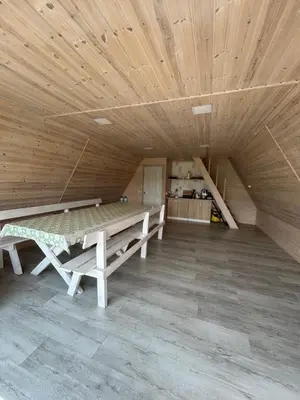 a room with wooden ceilings and a table and a kitchen at A-Spot - A-formos nameliai ir poilsio sodyba in Roglaičiai I