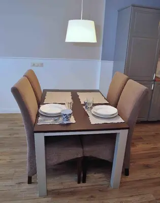 a dining room table with chairs and plates and a lamp at Dzuku apartment 11 in Vilnius