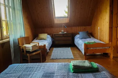 a bedroom with two beds and a chair and a window at Lake 4U in Užuguostis