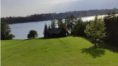 a house on a grassy hill next to a lake at Lake 4U in Užuguostis