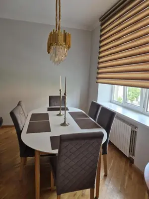 a dining room table with chairs and a chandelier at Boulevard house in Šiauliai