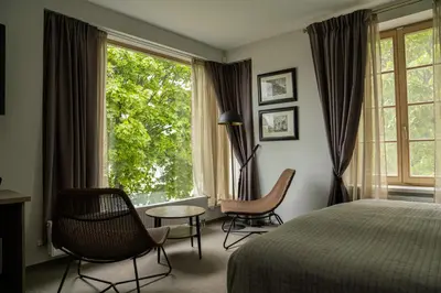 a bedroom with a bed and chairs and a window at Birštono Banginukas poilsio namai in Birštonas