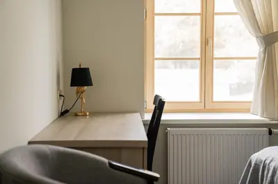 a desk with a lamp next to a window at Birštono Banginukas poilsio namai in Birštonas