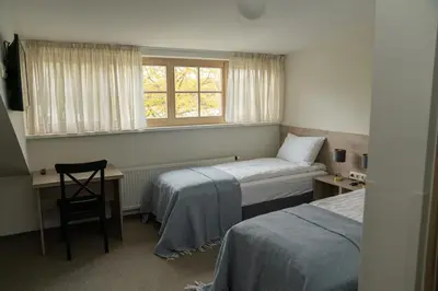 a room with two beds and a desk and a window at Birštono Banginukas poilsio namai in Birštonas