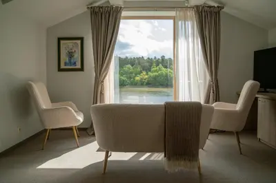a living room with a couch and a large window at Birštono Banginukas poilsio namai in Birštonas