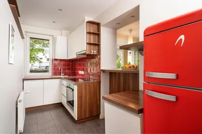 a red refrigerator in a kitchen with white cabinets at Apartment with big terrace in Vilnius