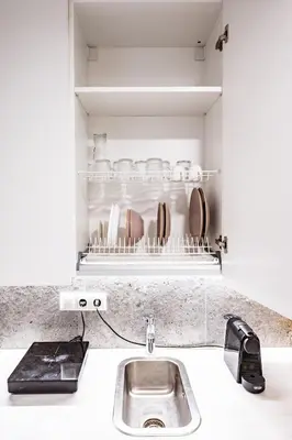 a kitchen counter with a sink and a shelf with dishes at Cozy 1BR in Old Town with FREE Parking in Vilnius