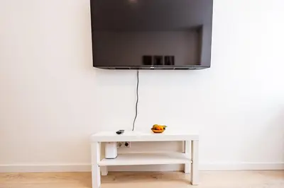 a white table with a tv on a white wall at Cozy 1BR in Old Town with FREE Parking in Vilnius