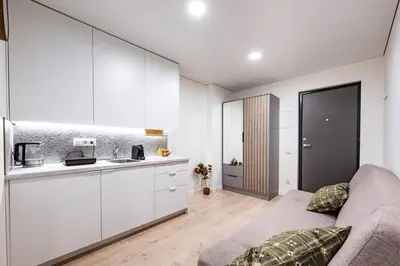 a kitchen with white cabinets and a couch in a room at Cozy 1BR in Old Town with FREE Parking in Vilnius