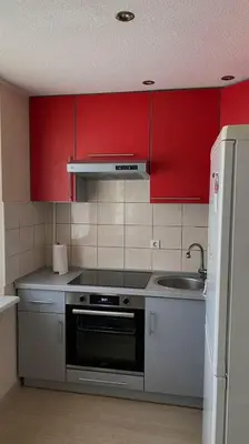 a kitchen with red cabinets and a stove and a sink at Ramybė Druskininkai in Druskininkai