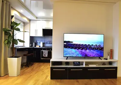 a flat screen tv sitting on a stand in a living room at Central Apartment with Fireplace & Cathedral View in Šiauliai
