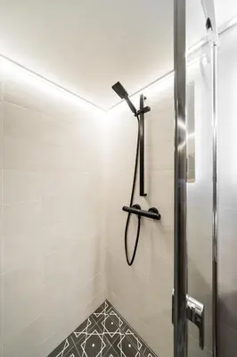 a shower in a bathroom with white tiles at Radio Apartment in Kaunas