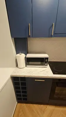 a kitchen with blue cabinets and a microwave on a counter at CITY STAY 2-bedroom apartment in Šiauliai