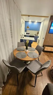 a dining table and chairs with a kitchen in the background at CITY STAY 2-bedroom apartment in Šiauliai