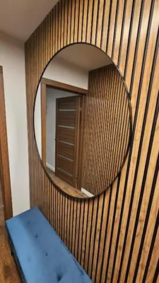 a circular mirror on a wooden wall with a blue bench at CITY STAY 2-bedroom apartment in Šiauliai