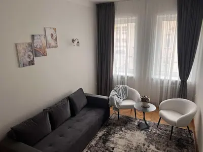 a living room with a black couch and two chairs at Vytauto apartamentai centre in Kaunas