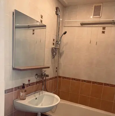 a bathroom with a sink and a shower with a mirror at Butas Trakuose su vaizdu į ežerus-Lake view apartment in Trakai in Trakai