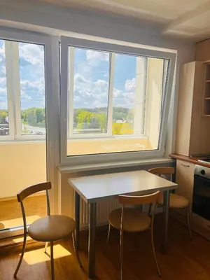 a kitchen with a table and chairs and two windows at Butas Trakuose su vaizdu į ežerus-Lake view apartment in Trakai in Trakai