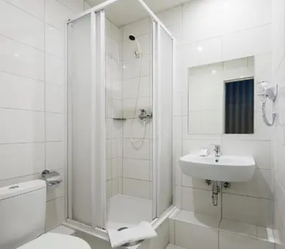 a white bathroom with a shower and a sink at Naujamiescio Studio in Vilnius