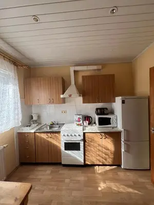 a kitchen with wooden cabinets and a white refrigerator at Cozy Maumedziu apartment in Vilnius