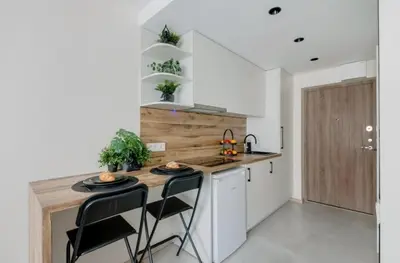 a kitchen with a counter with chairs and a sink at Green Apartment in Vilnius