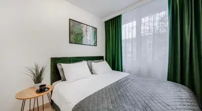 a bedroom with a large bed with green curtains at Green Apartment in Vilnius