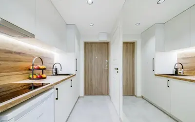 a kitchen with white cabinets and a wooden door at Green Apartment in Vilnius