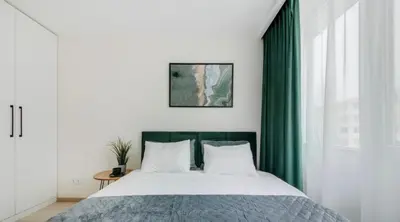 a bedroom with a large bed with green curtains at Green Apartment in Vilnius