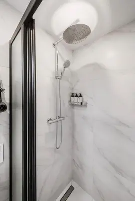 a shower in a bathroom with white marble at Green Apartment in Vilnius