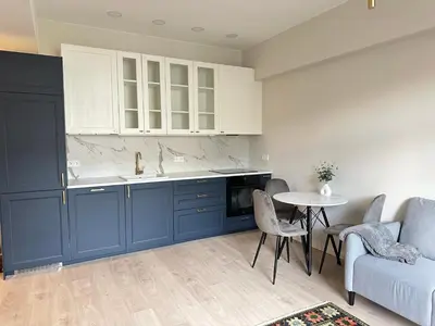 a kitchen with blue cabinets and a table and a couch at Cozy City Center Apartment in Kaunas