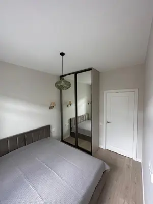 a white bedroom with a bed and a mirror at Cozy City Center Apartment in Kaunas