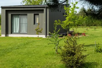 a small house in a yard with a green lawn at Rasota Pieva Dewy Meadow