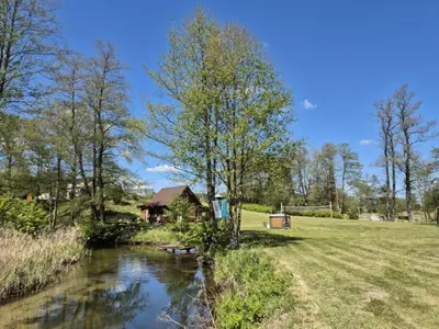 a house next to a river in a field at Sodyba LAIMĖS SLĖNIS in Kapčiamiestis